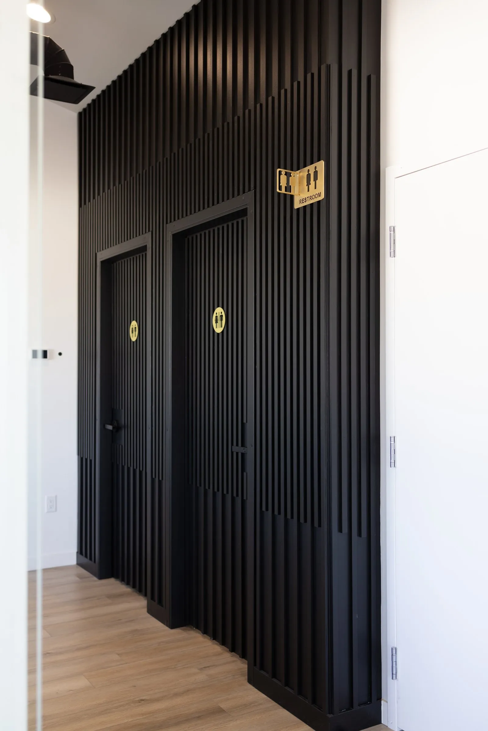 The bathrooms, black slatted doors with gold signs off a bright hallway