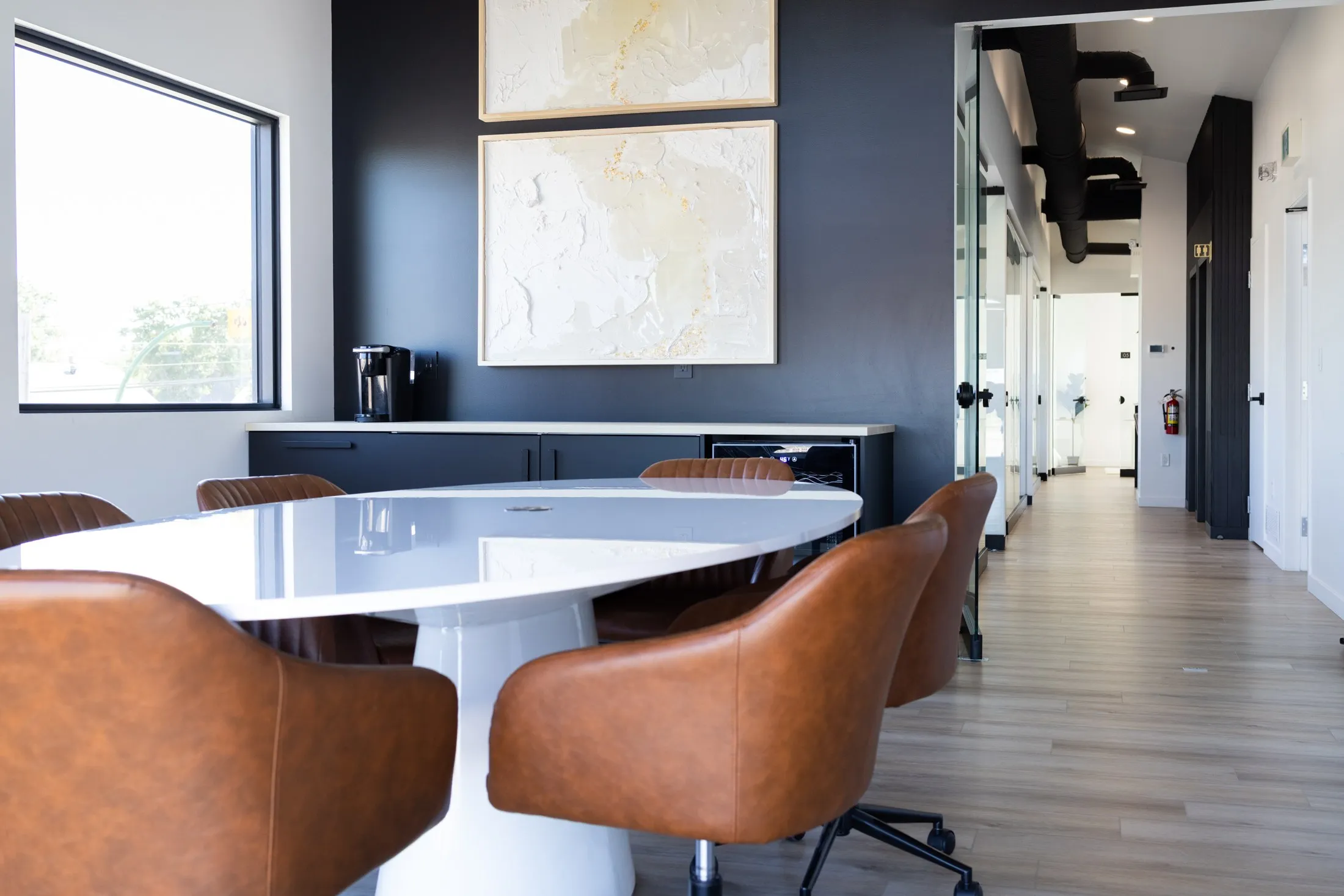 The boardroom from the door, the white table, leather chairs and the art above the counter