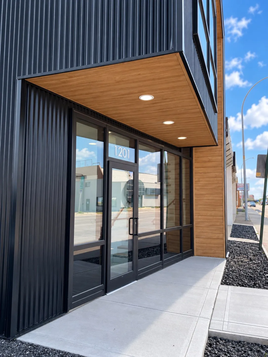 The SLANT entrance, the glass doors with 1201 above them under the wood soffit and its downlights